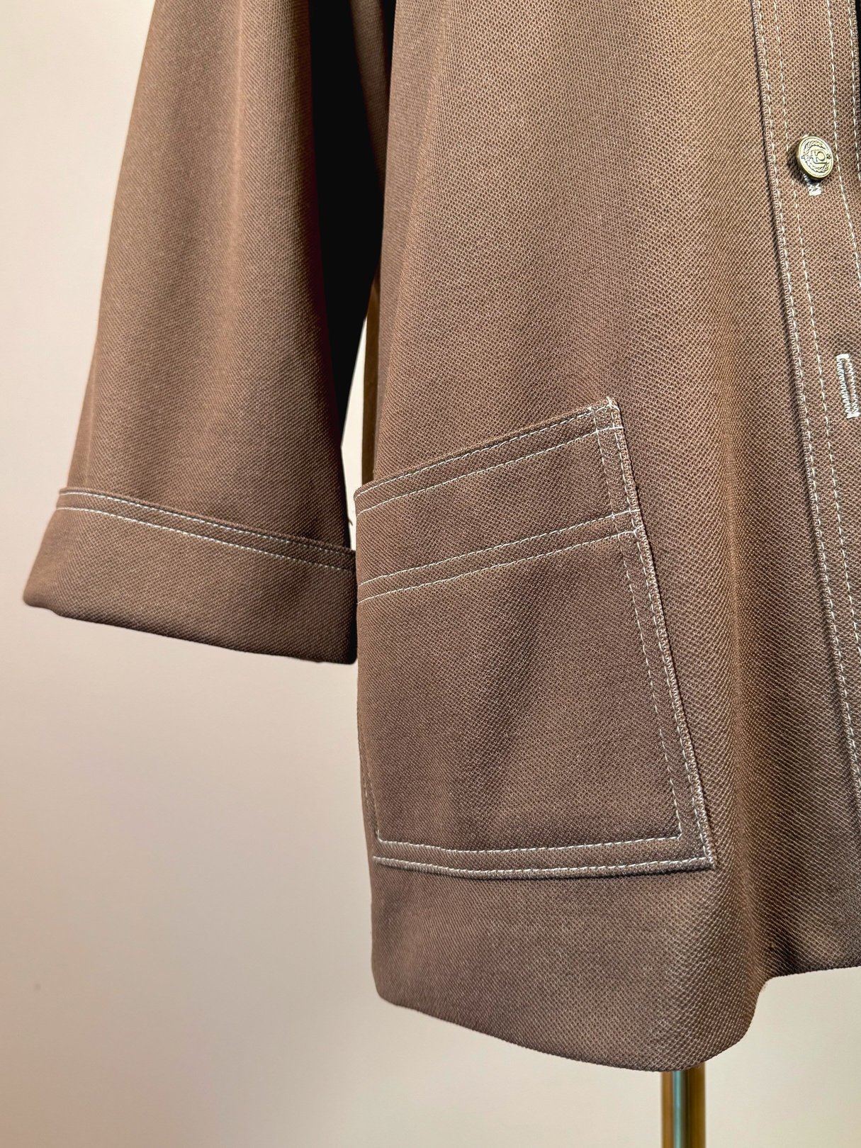 Brown 1960s women's jacket featuring a cropped sleeve and contrasting white stitching on the pockets.