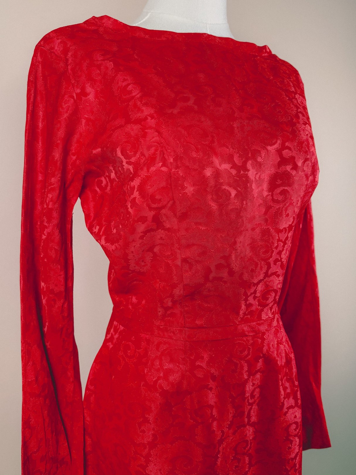 Red 1950s damask dress for women with long sleeves and a textured pattern.