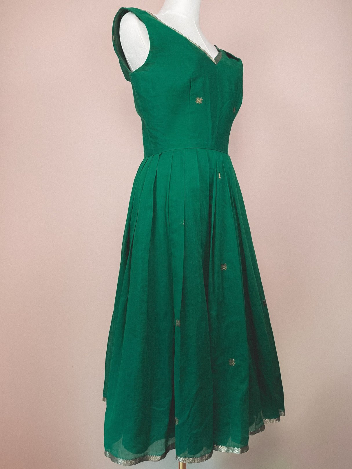 A 1950s women's dress in vibrant green with a fitted bodice and a flowing skirt featuring starburst embellishments.