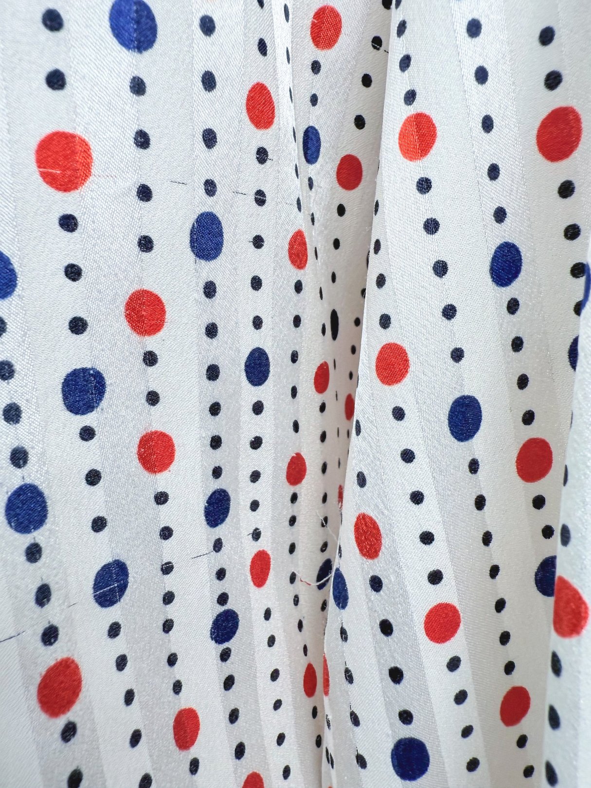 Red and white blouse with polka dot pattern in red and navy blue, reflecting 1980s style for women.