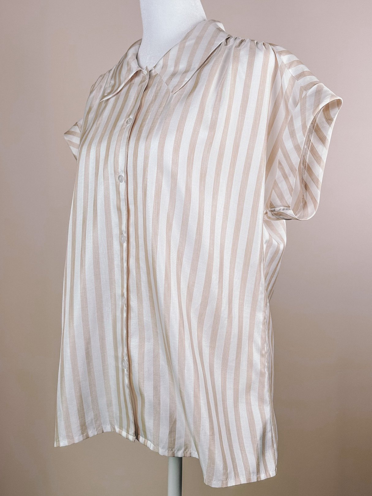 Chic 1970s striped blouse in classic retro white with tan and blush stripes, featuring a button-down front and short sleeves.