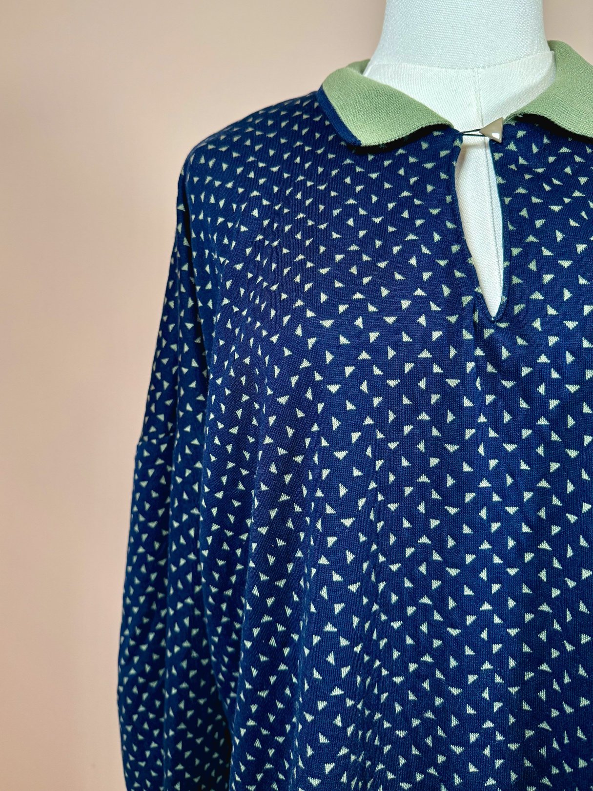 Navy blue 1980s women's triangle print top featuring a green collar and a keyhole neckline.
