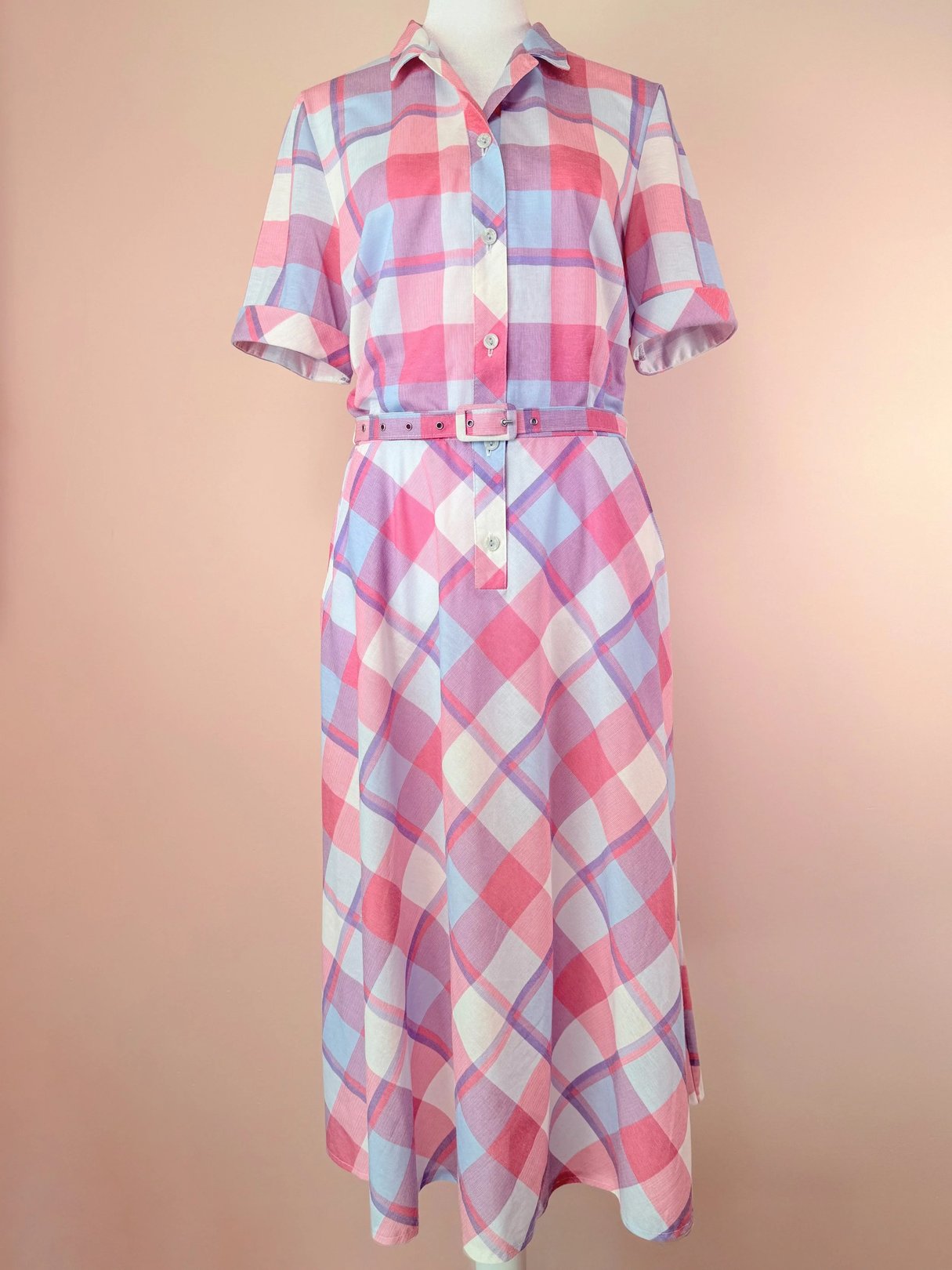 Short-sleeve plaid dress in pink and purple tones with a belted waist.