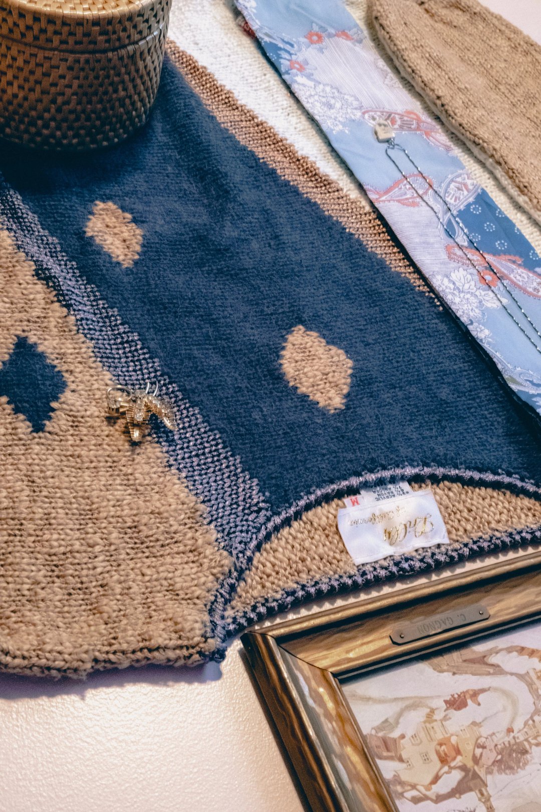 A textured rug featuring a blue and natural color pattern with a decorative pin and framed artwork nearby.