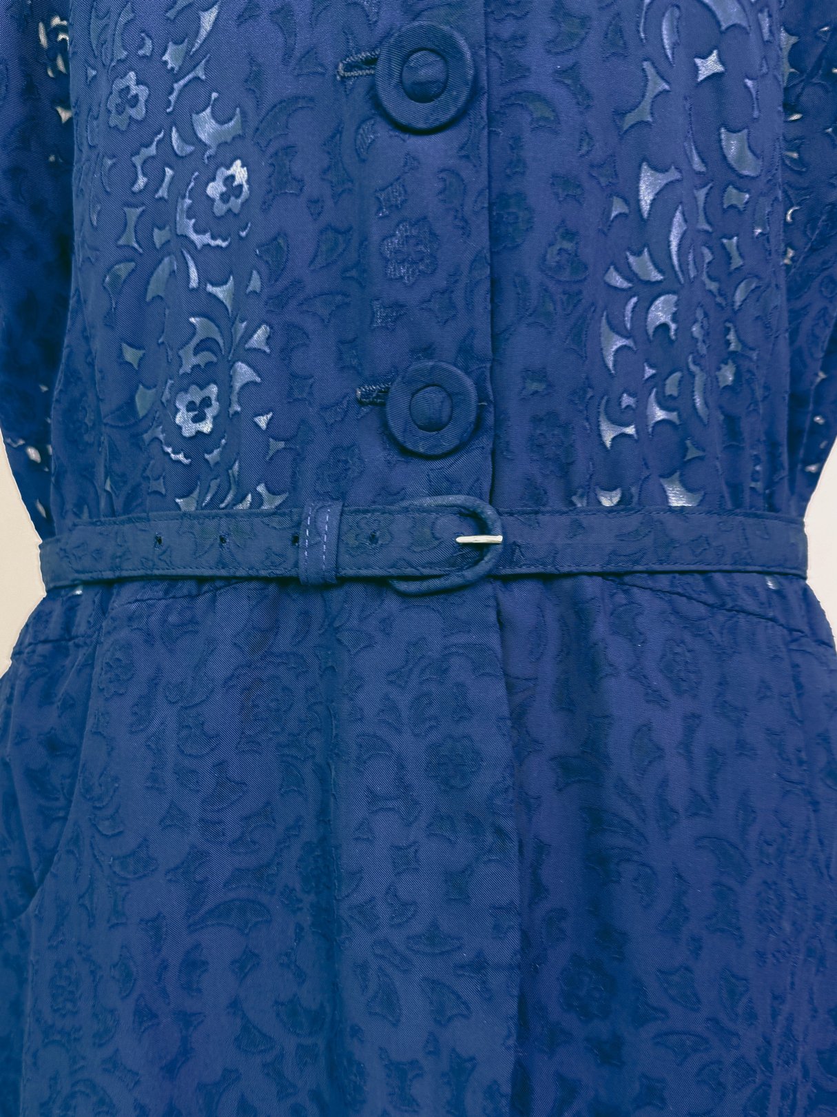 Navy blue 1940s French Café dress featuring a textured floral pattern, button front, and a matching belt.