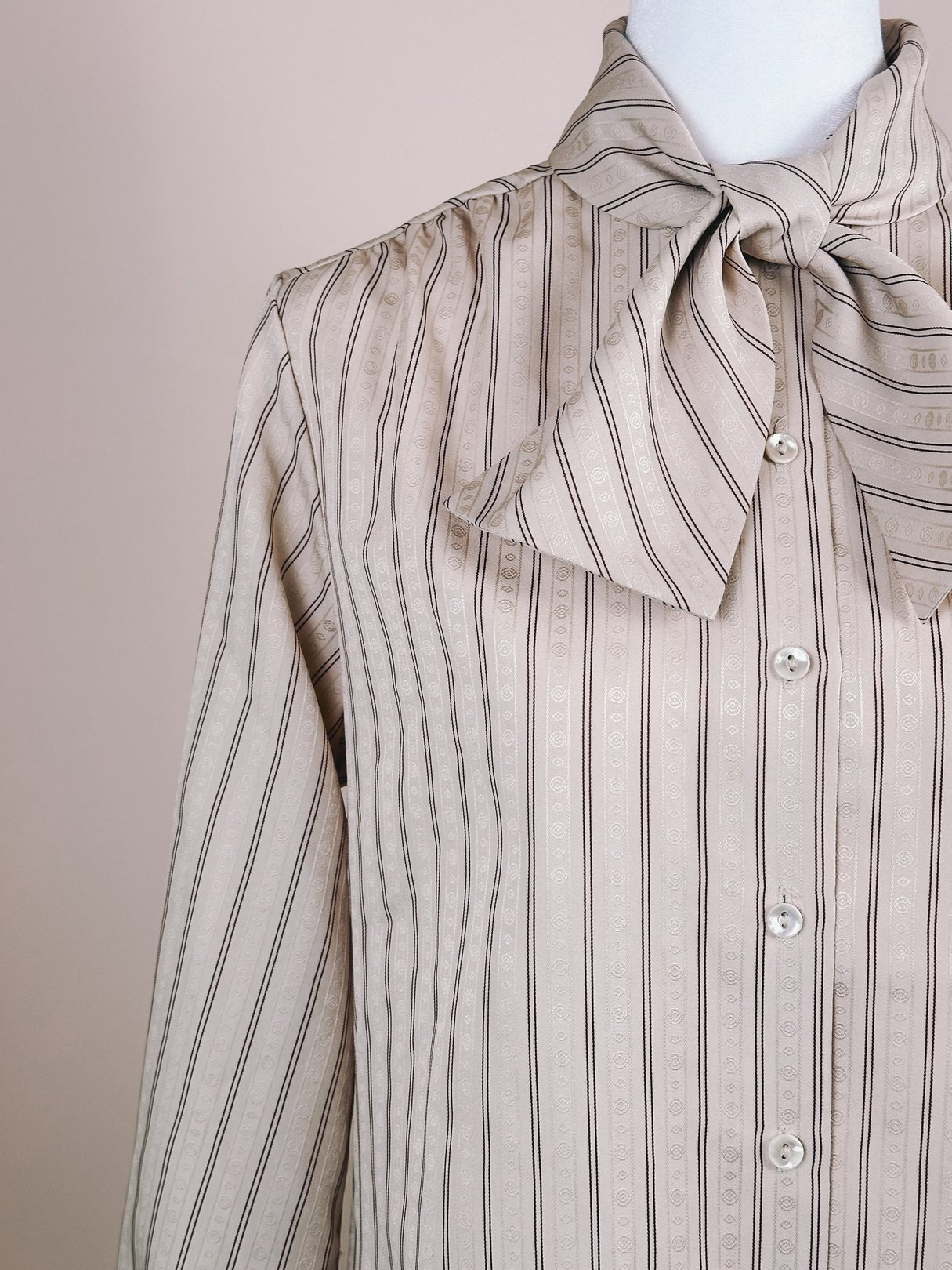 A tan blouse featuring maroon stripes and a bow tie collar, indicative of 1980s fashion for women.