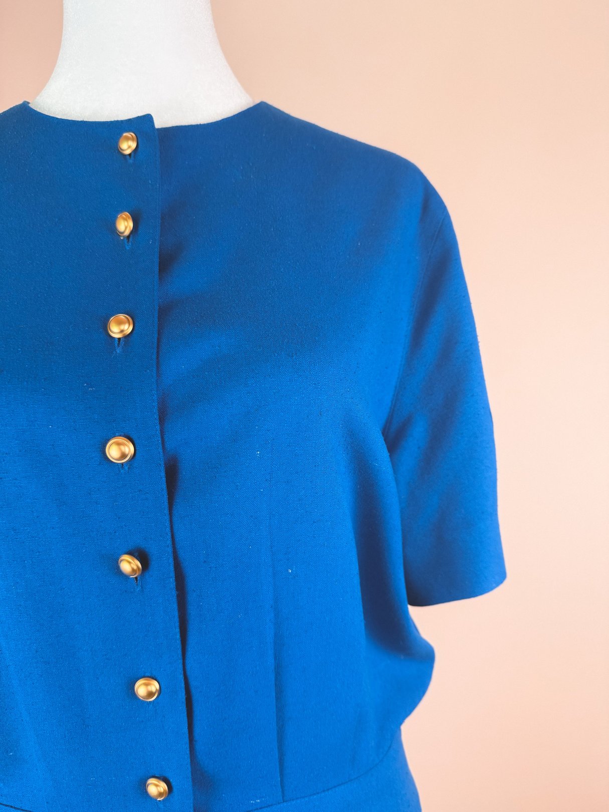 Cerulean blue women's dress from the 1980s featuring short sleeves and gold buttons down the front.