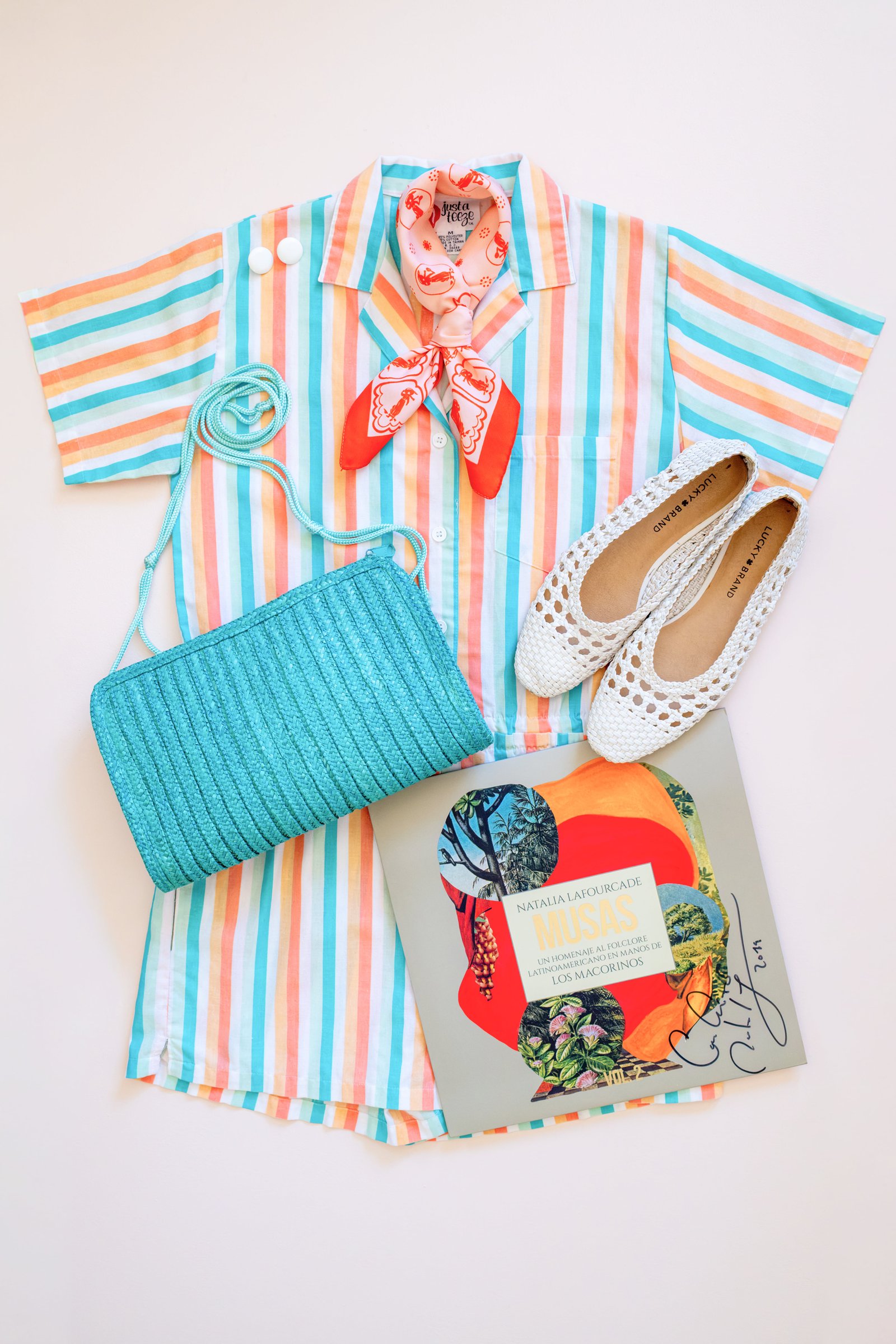 Inspired by Summer, Styled by Music gallery image: A colorful striped shirt accompanied by a red scarf, a turquoise woven crossbody bag, white shoes, and a music-themed album cover.