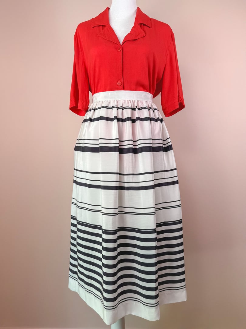 1970s women's white skirt with black stripes, featuring a fitted waistband and a flared design, paired with a red top.