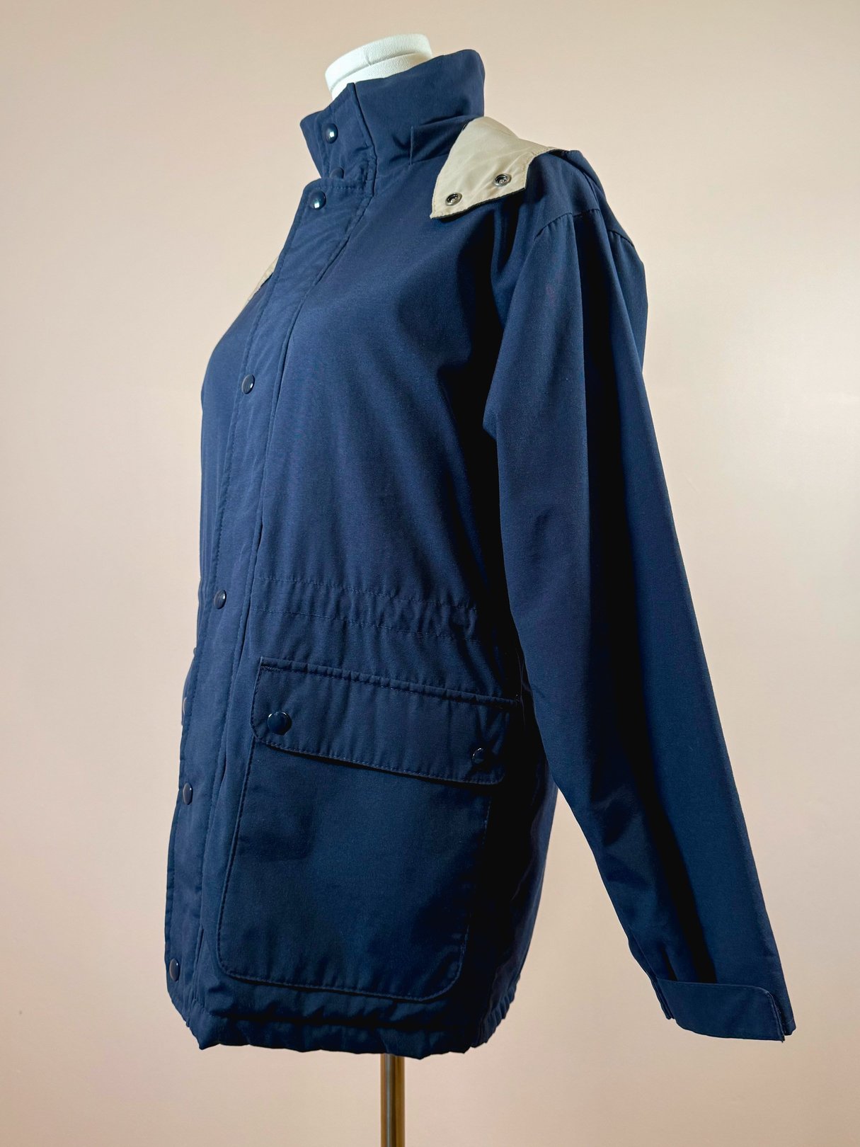 Navy blue women's utility field coat from the 1970s featuring a snap closure and side pocket.