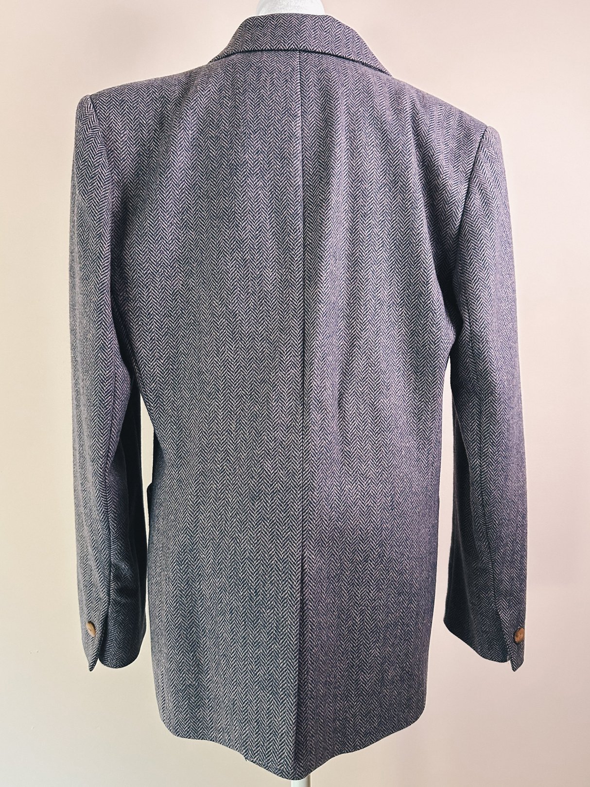 Mauve pink women's 1970s Scholastic tweed blazer featuring a herringbone pattern and button details on the sleeves, shown from the back.