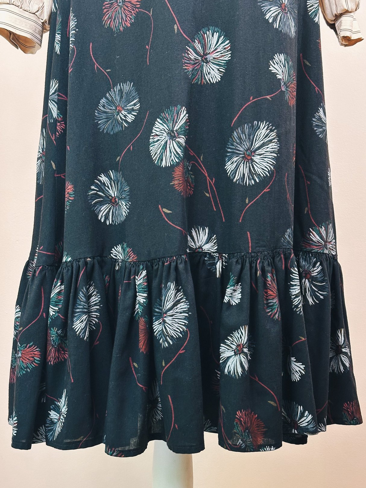 Black Dandelion Ruffle Skirt featuring a floral print and a ruffled hem, inspired by 1970s fashion.