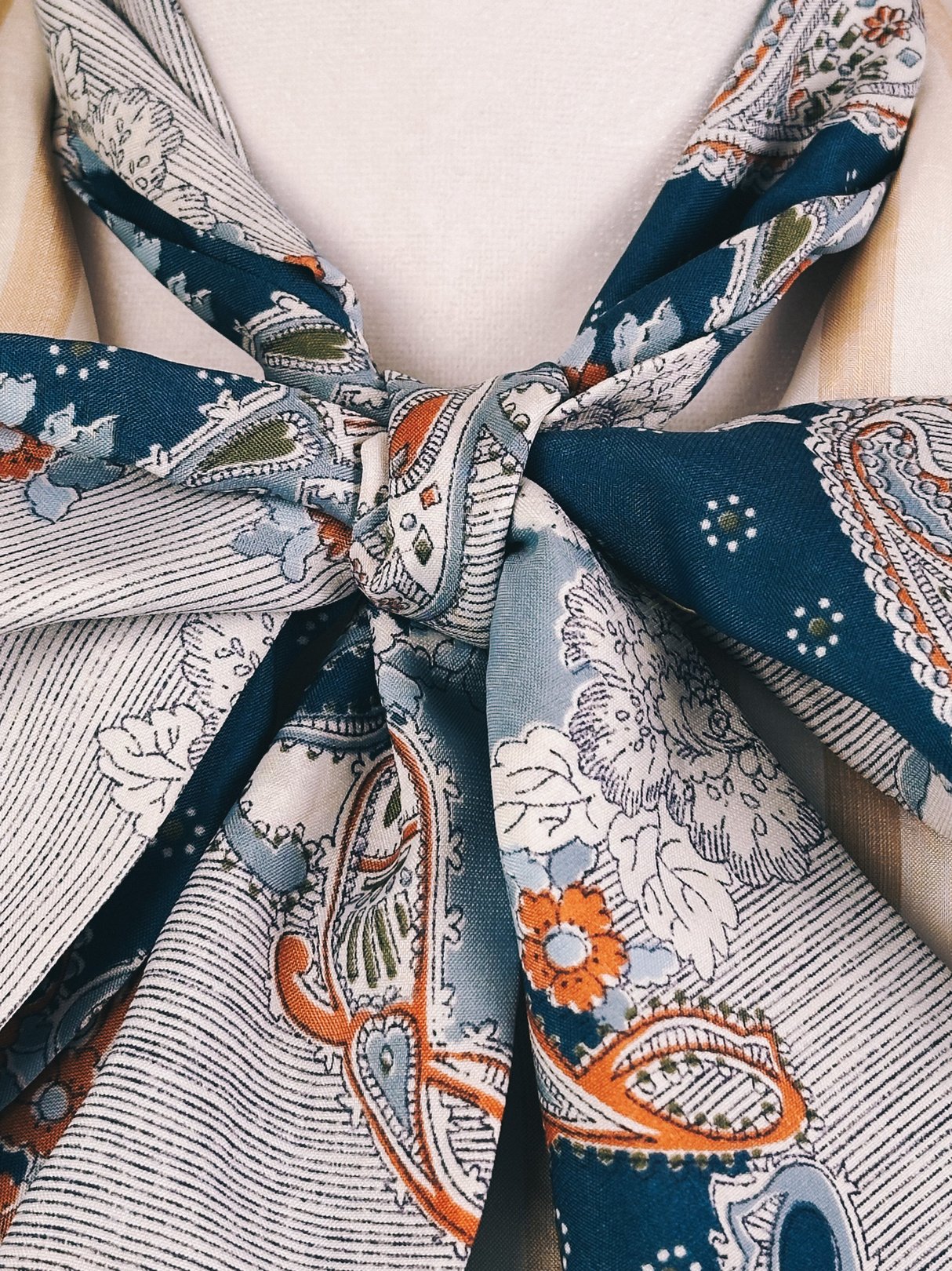 Light blue paisley scarf with floral patterns tied elegantly, representing women's accessories from the 1970s.