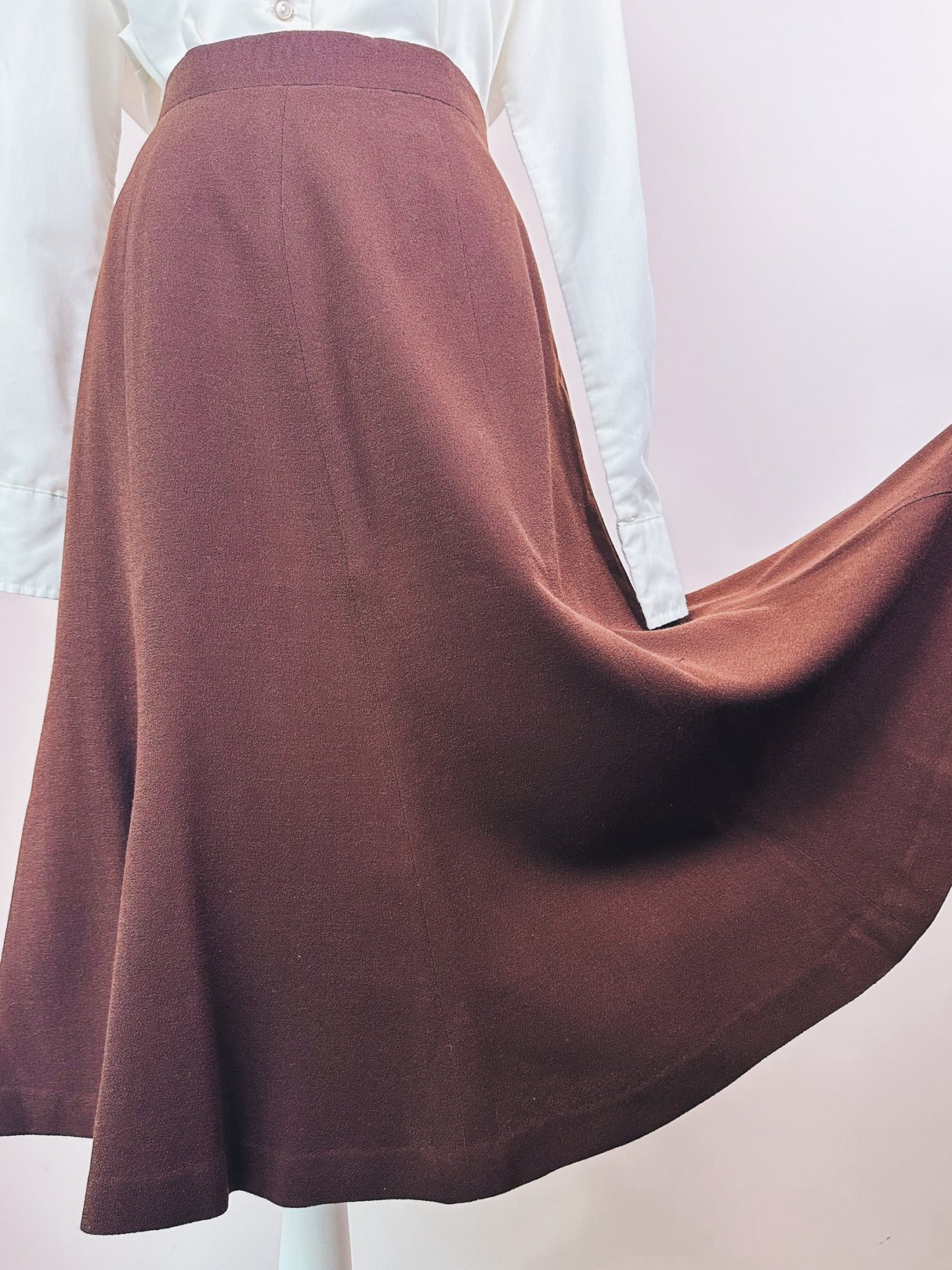 Brown 1970s women's skirt with a flared design displayed on a mannequin against a light background.