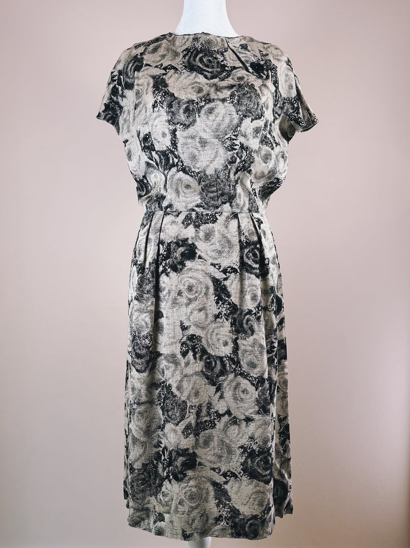 Black and cream 1950s rose-patterned dress with short sleeves and a cinched waist.