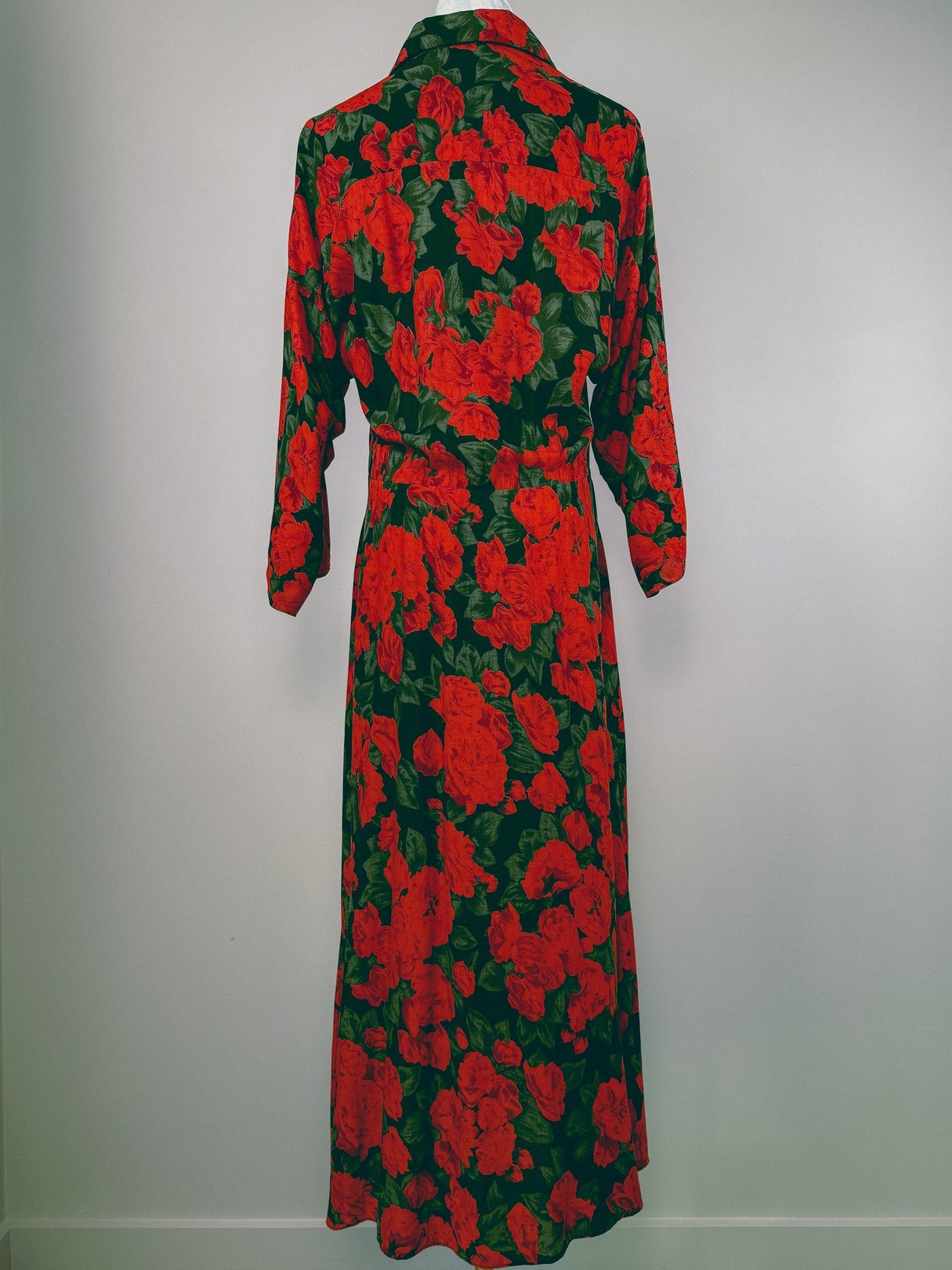 Long-sleeved, ankle-length dress featuring a vibrant red floral pattern on a dark green background, showcasing a 1990s style.