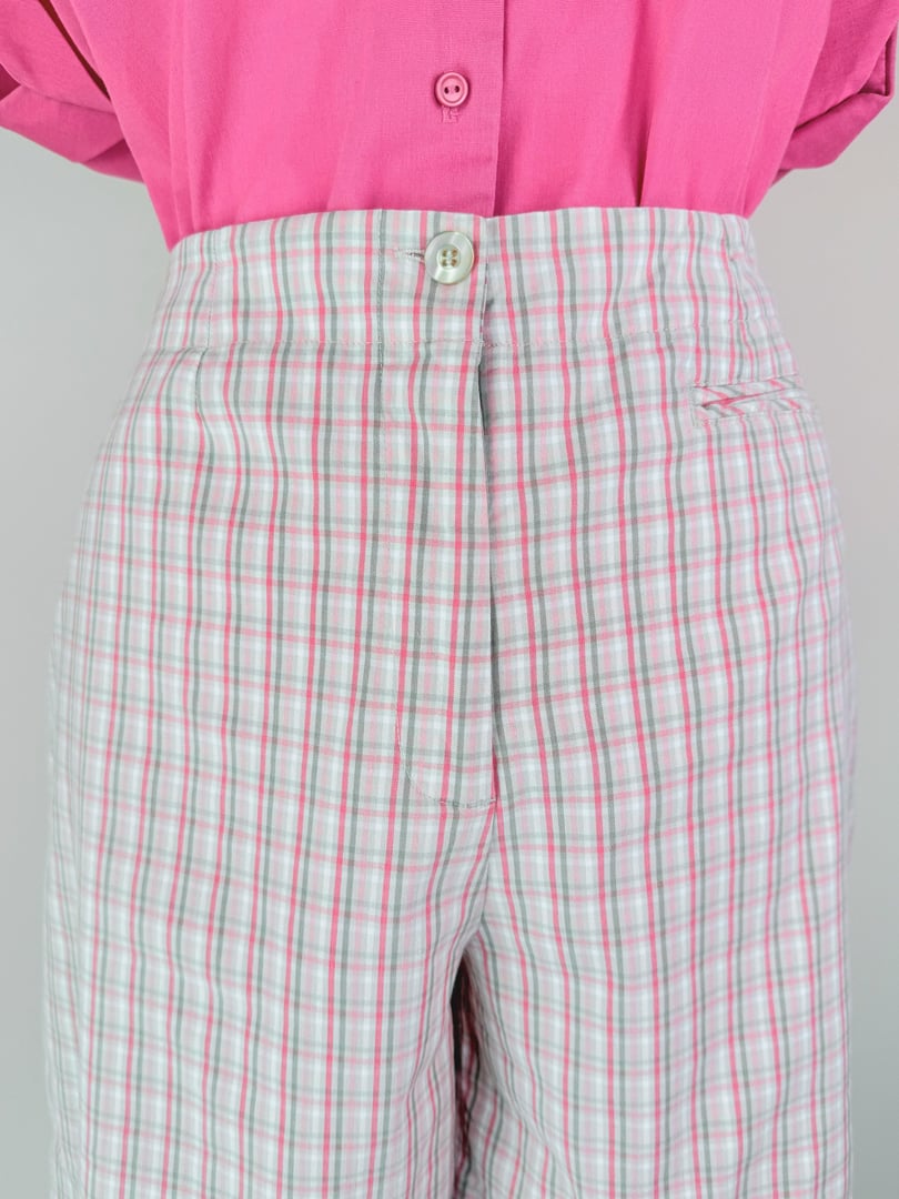 High-waisted pink plaid shorts featuring a button closure and side pocket, styled with a matching pink blouse.
