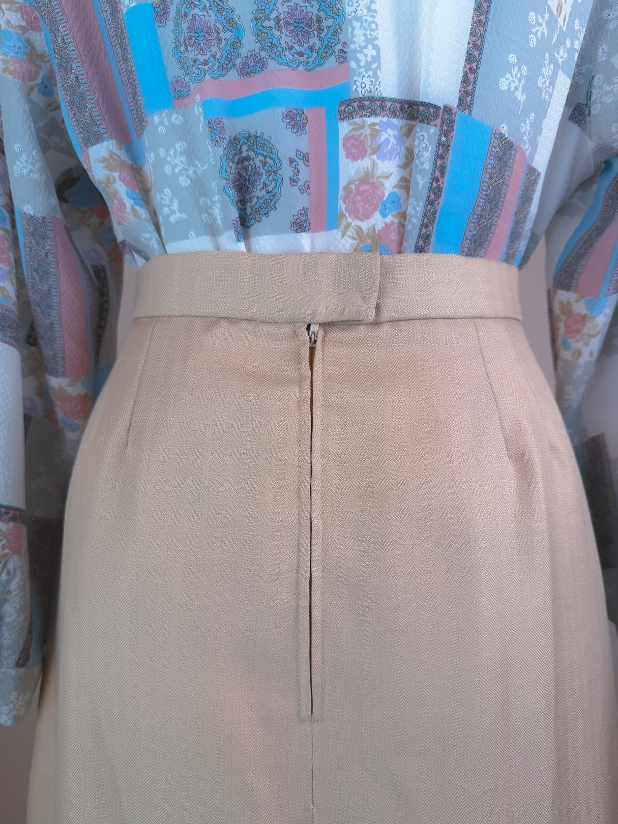 Cream beige women's skirt from the 1960s featuring a back zipper and a tailored silhouette.