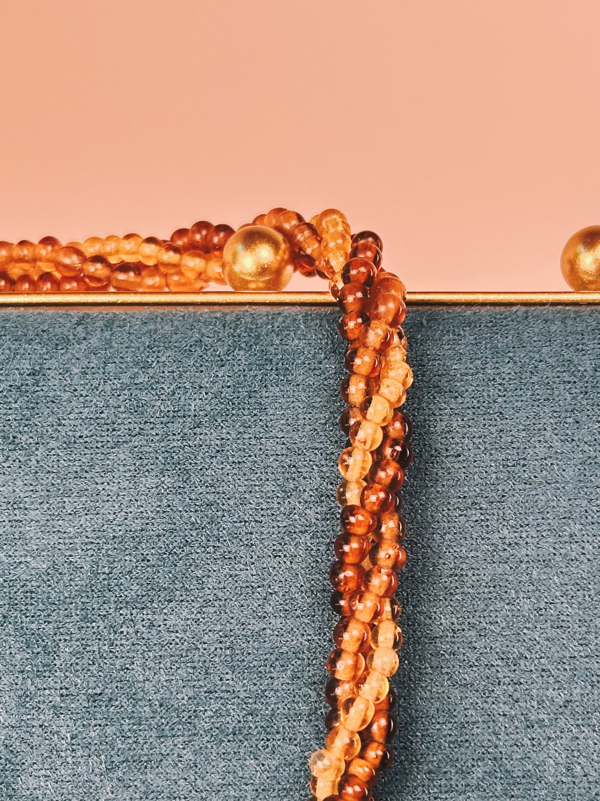 A 1970s-inspired amber beaded necklace featuring a variety of amber shades and gold accents.