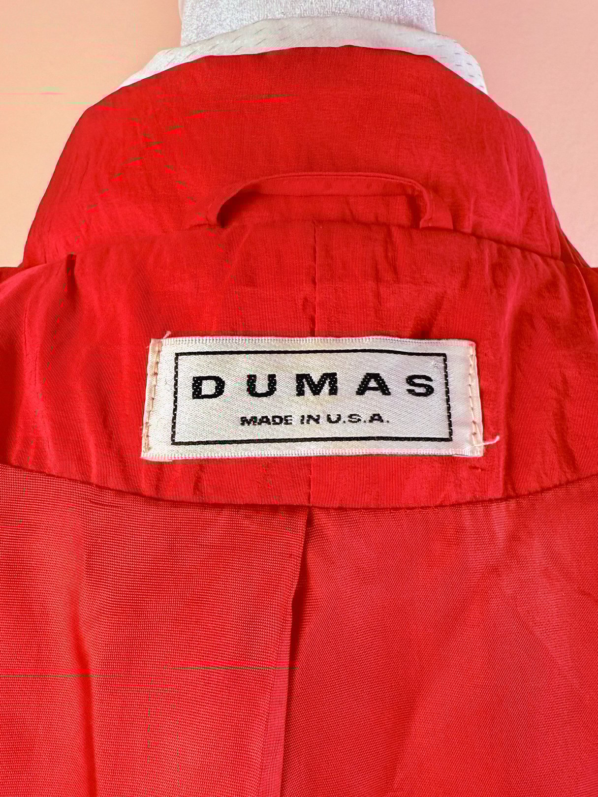 Red women's rain jacket from the 1980s with a label reading "DUMAS MADE IN U.S.A.