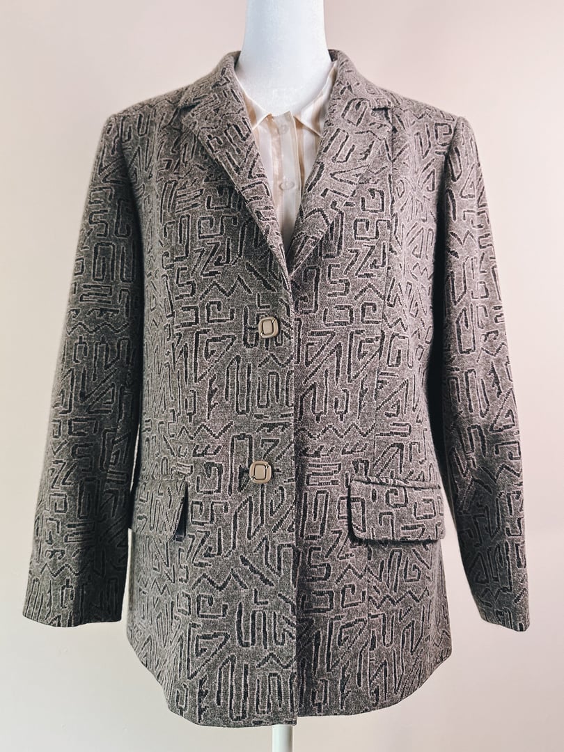 A women's 1980s geometric blazer in pink with a textured pattern, featuring two front pockets and a double-button closure.