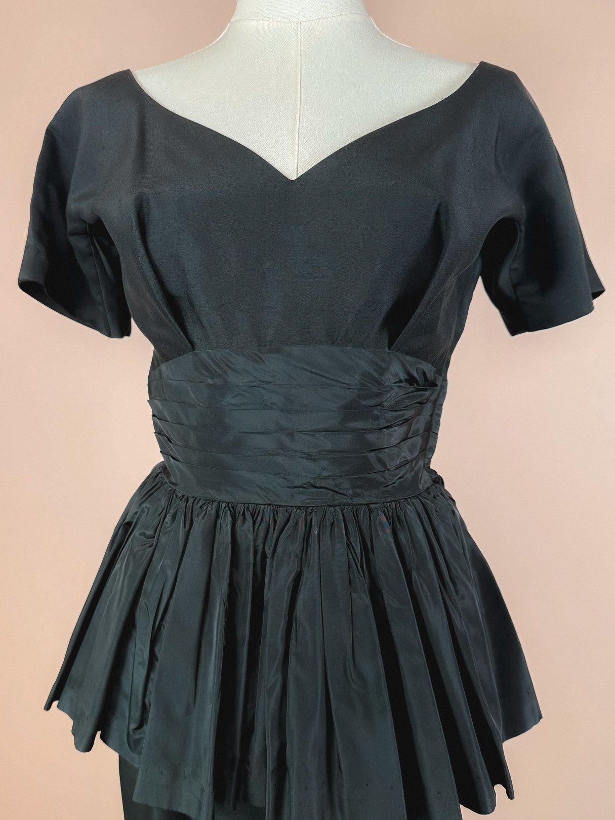 Black 1950s-inspired New Years Starlet Dress featuring a structured short-sleeve bodice and a gathered peplum skirt.