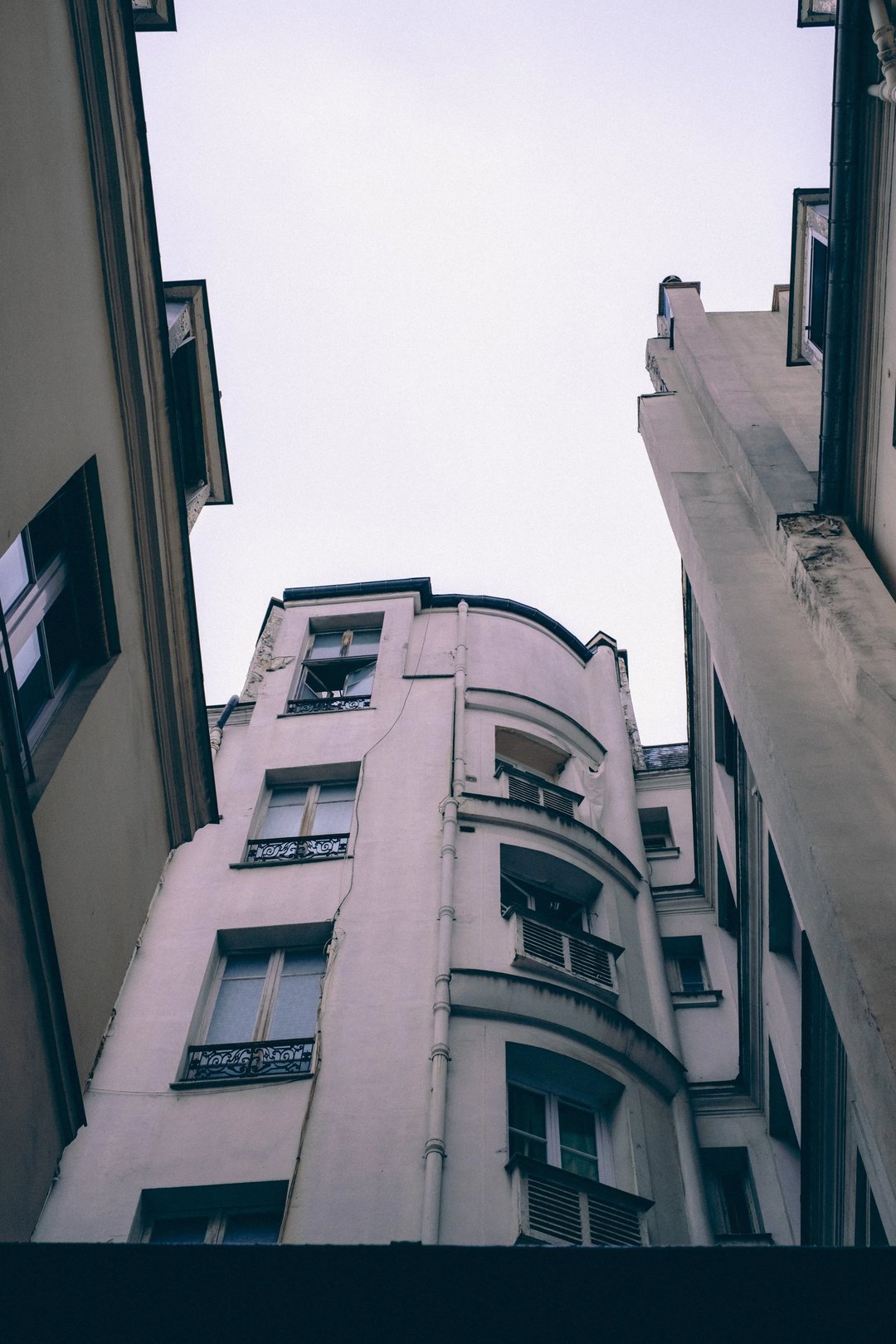 A view of a narrow alleyway between two buildings, showcasing architecture from below.