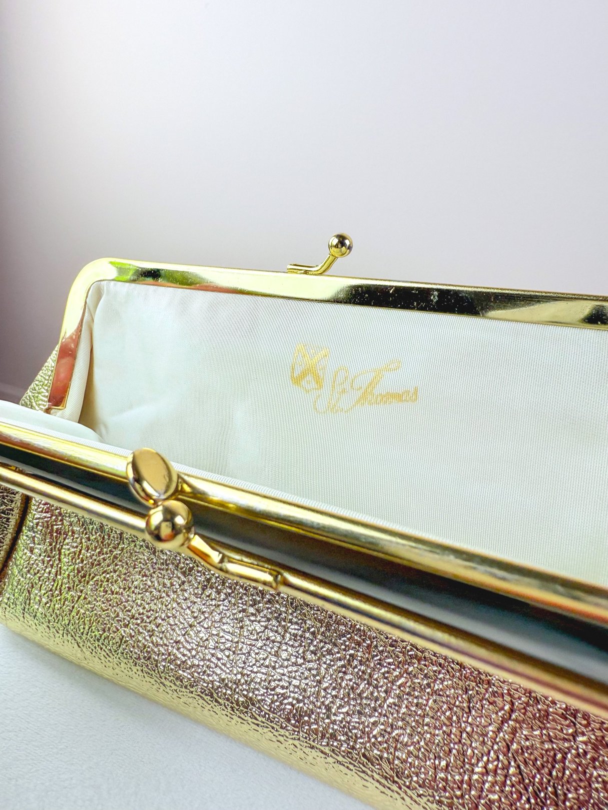 Women’s 1950s Gold Coast Clutch with a metallic gold finish and a white interior featuring the St. Thomas logo.