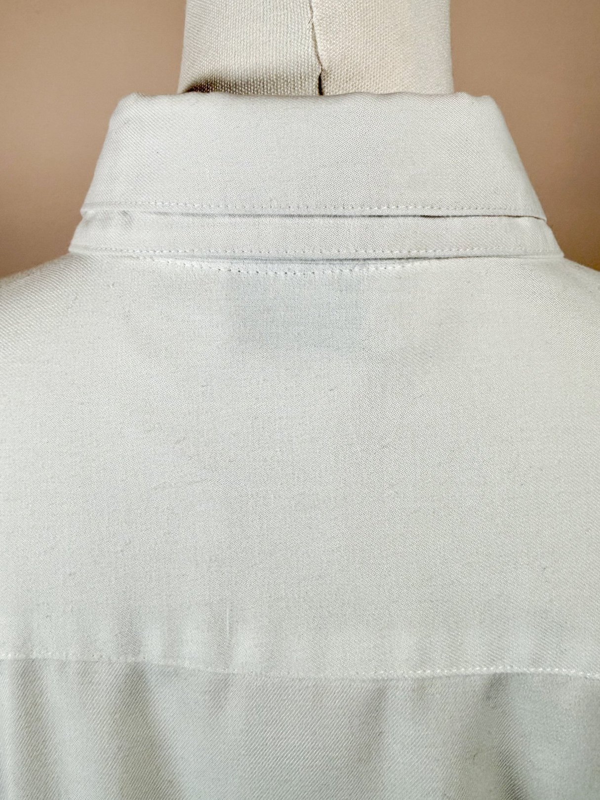 White cotton shirt featuring an embroidered design, shown from the back with a classic collar, indicative of 1970s women's fashion.