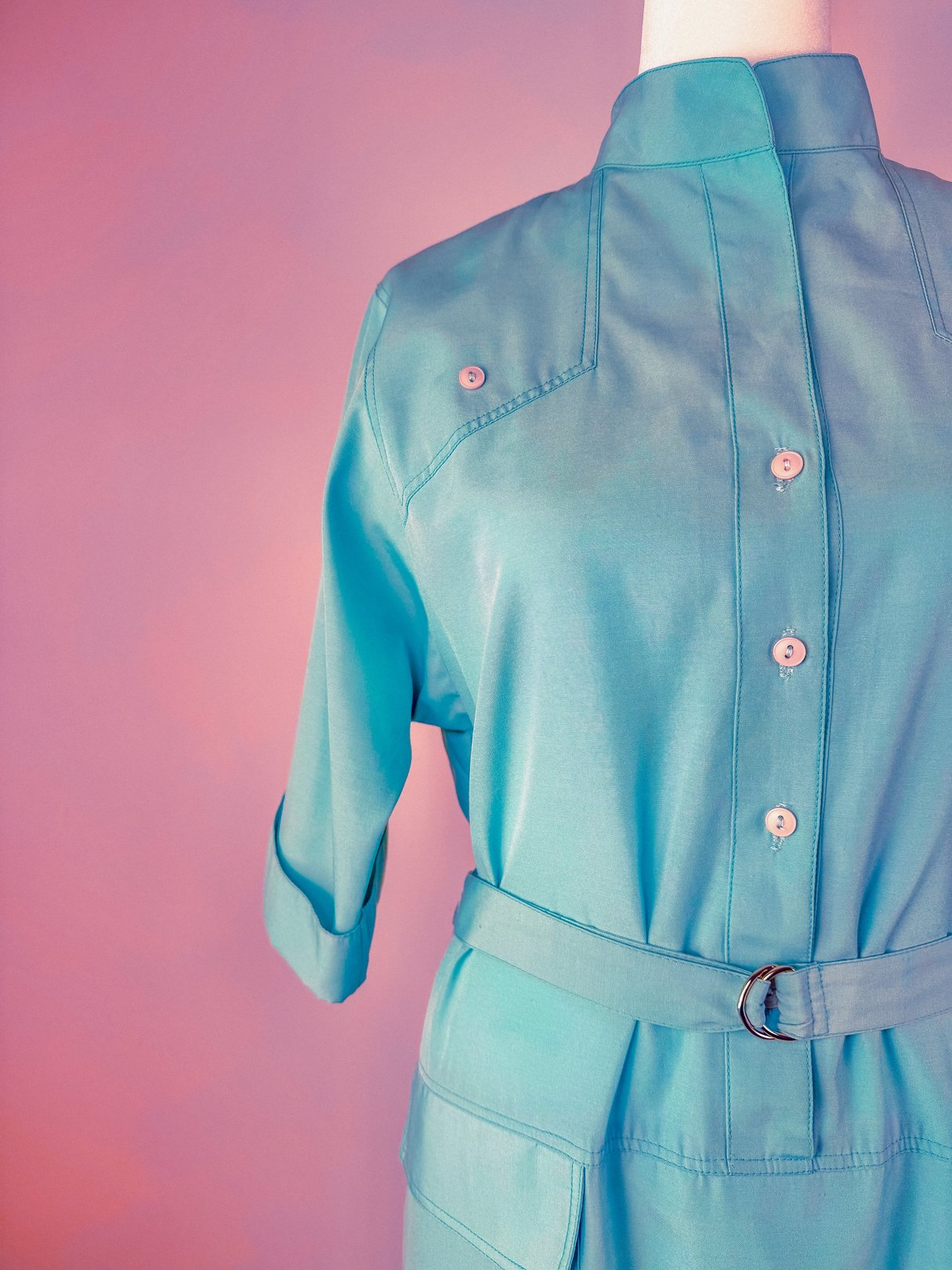 Skyline Shift Dress in sky blue featuring a high collar, button details, and a belt at the waist, evoking a 1960s style.