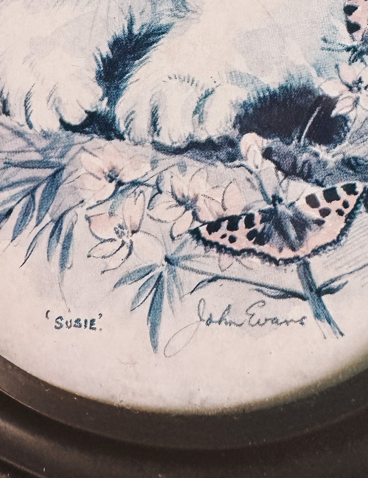A blue 1970s portrait of a cat named Susie, featuring flowers and a butterfly, with an artist signature.