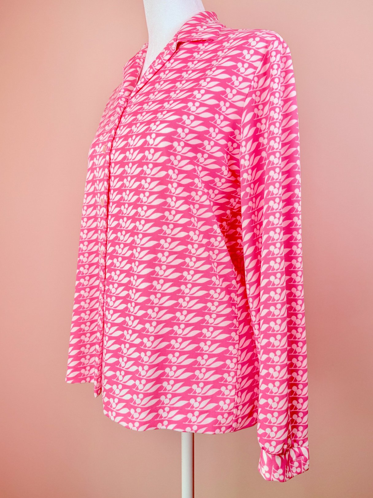 Pink 1970s women's blouse with a cherry petal print and long sleeves.