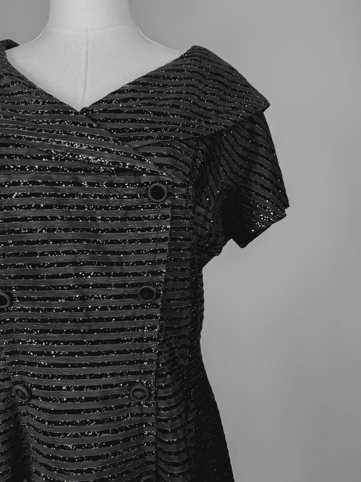 1950s women's black confetti party dress featuring a structured collar and horizontal stripe design.