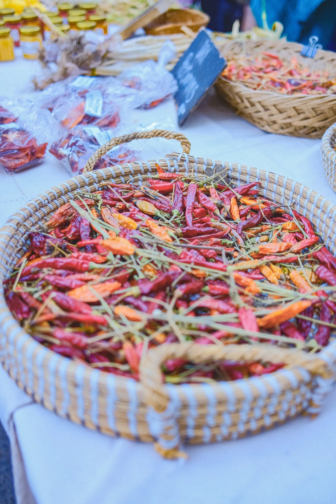 A woven basket filled with an assortment of dried red and orange chili peppers.