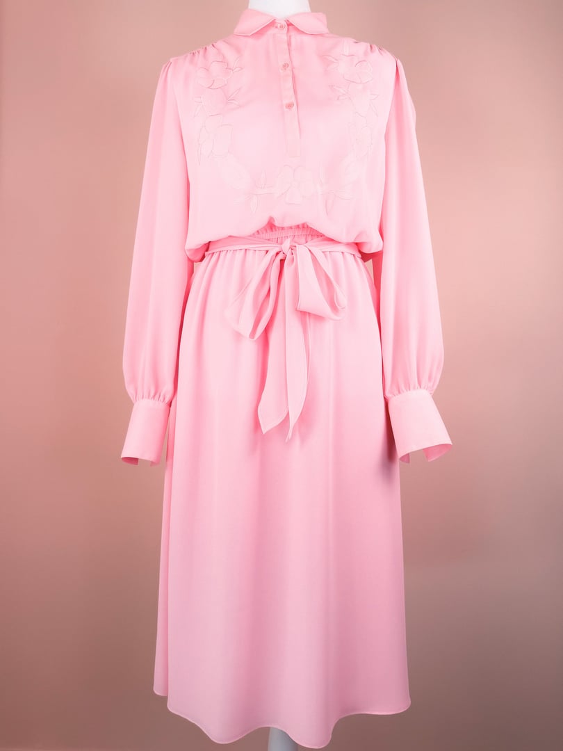 1980s women's bubble gum pink Flora Belle dress featuring long sleeves, a belted waist, and floral embroidery on the bodice.