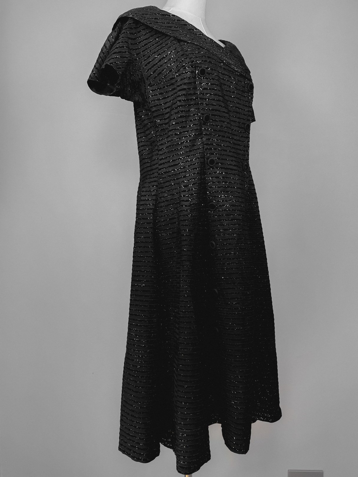 Black 1950s-style confetti party dress featuring a button-up front and short sleeves.