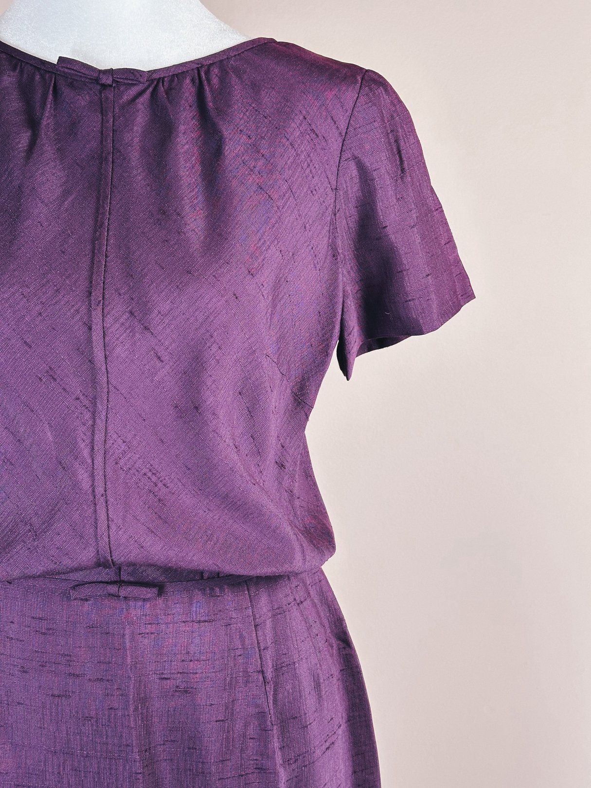 Short-sleeved purple dress featuring a bow detail, characteristic of 1960s women's fashion.