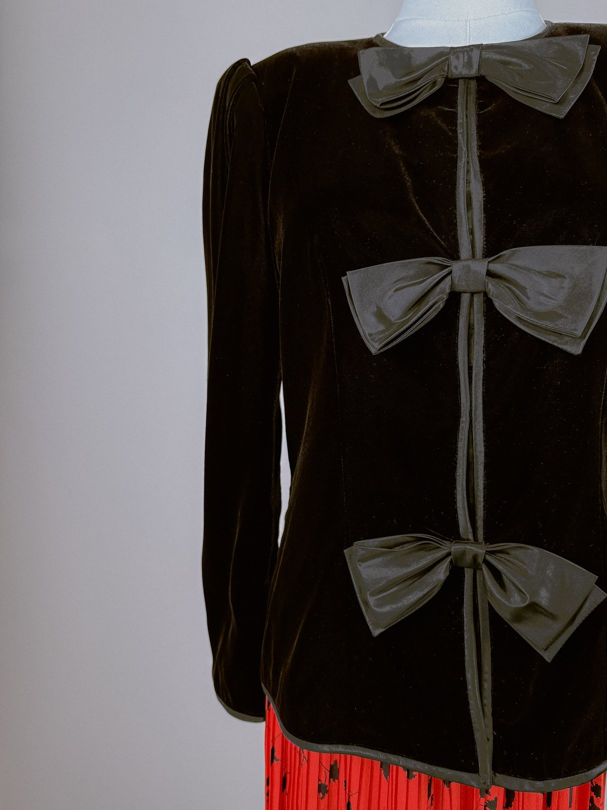 Black velvet women's jacket from the 1980s featuring prominent bows on the front.