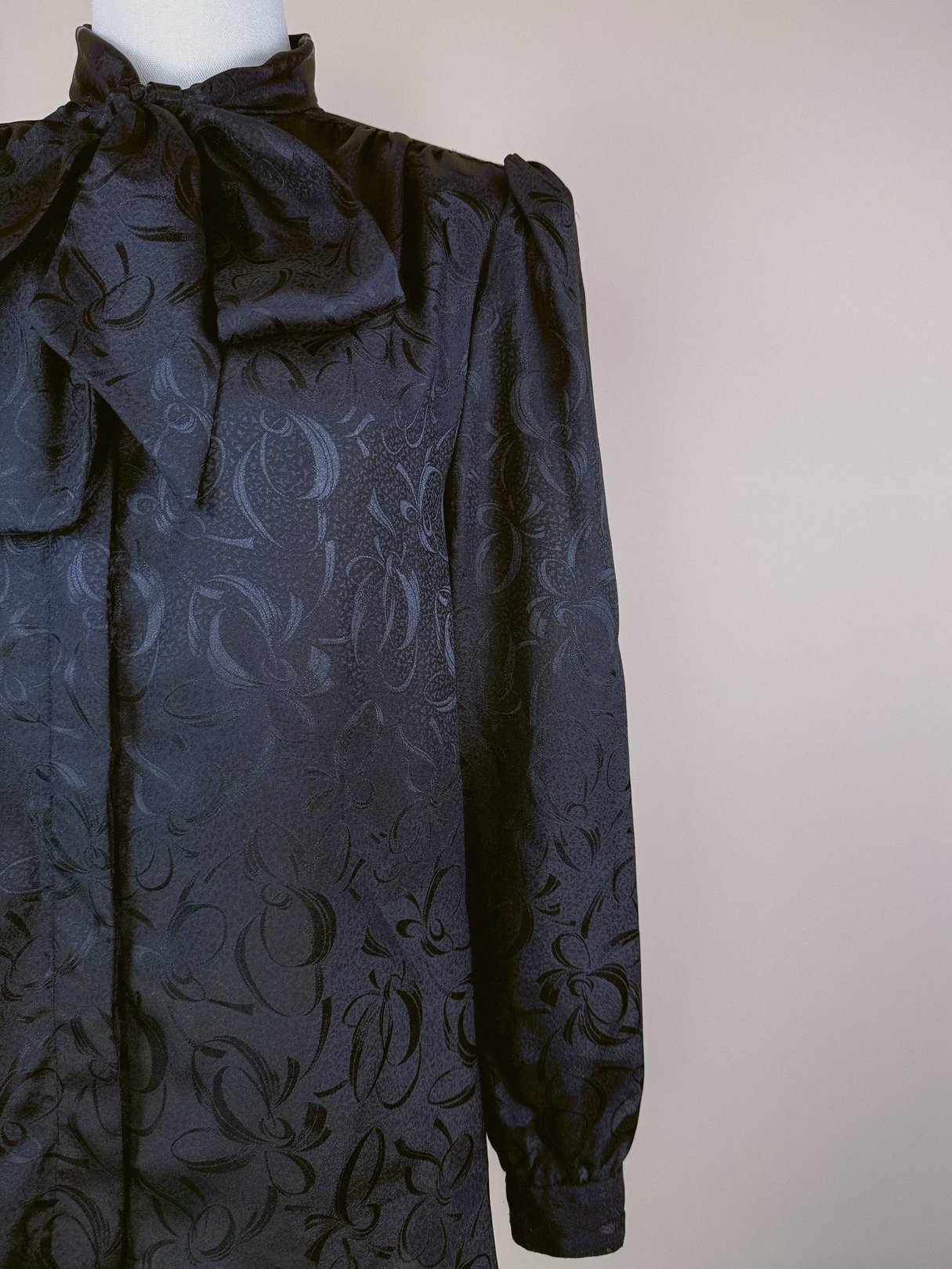 Black ink bow top for women from the 1980s, featuring a textured pattern and long sleeves.