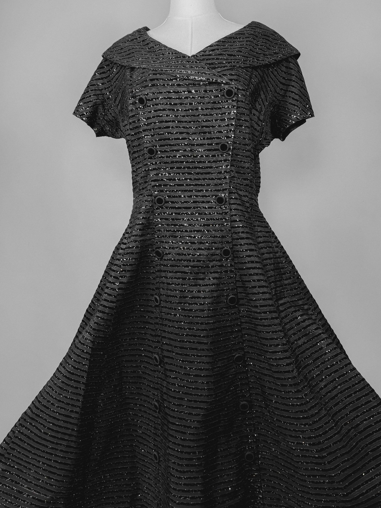 Black 1950s confetti party dress featuring a V-neckline, short sleeves, and a flared skirt with button details.