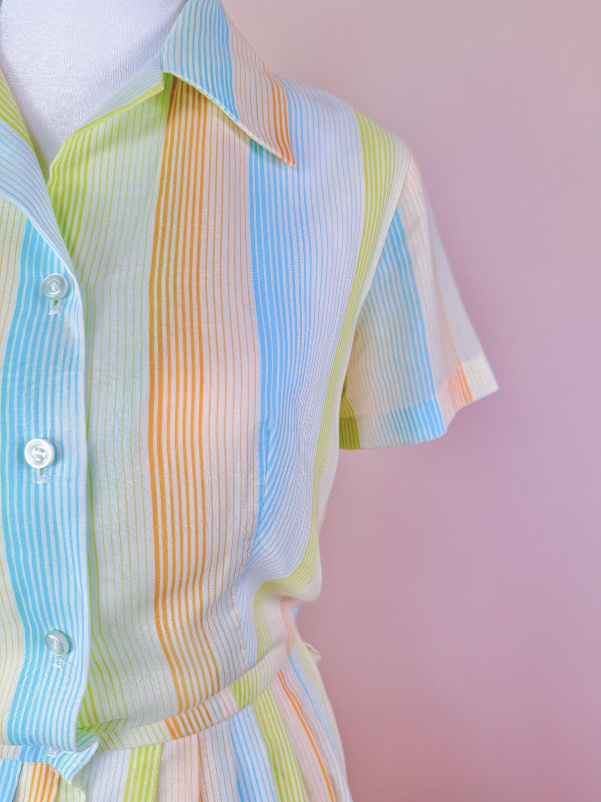 1950s women's Citrus Dress featuring vertical stripes in orange, blue, yellow, and green with a short-sleeved design and button-up front.