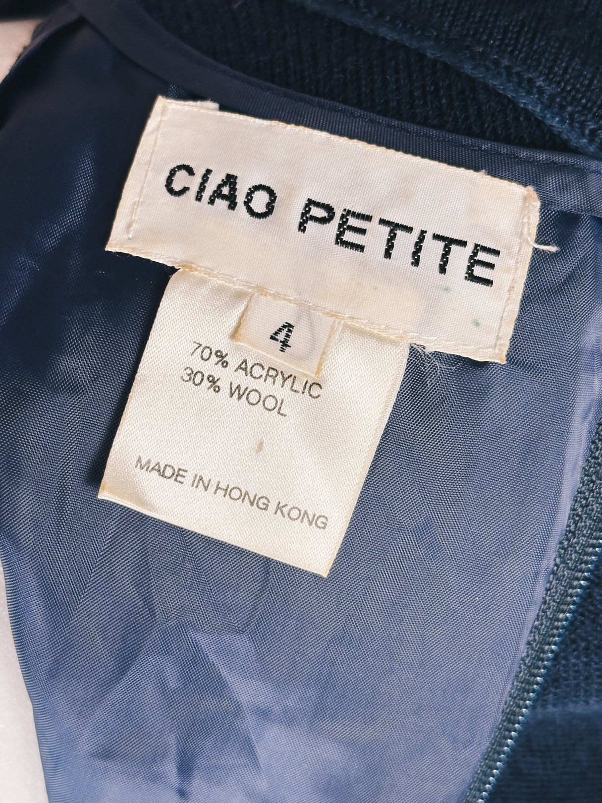 Navy blue 1980s women's sweater dress with a tag indicating a size 4 and fabric composition of 70% acrylic and 30% wool.