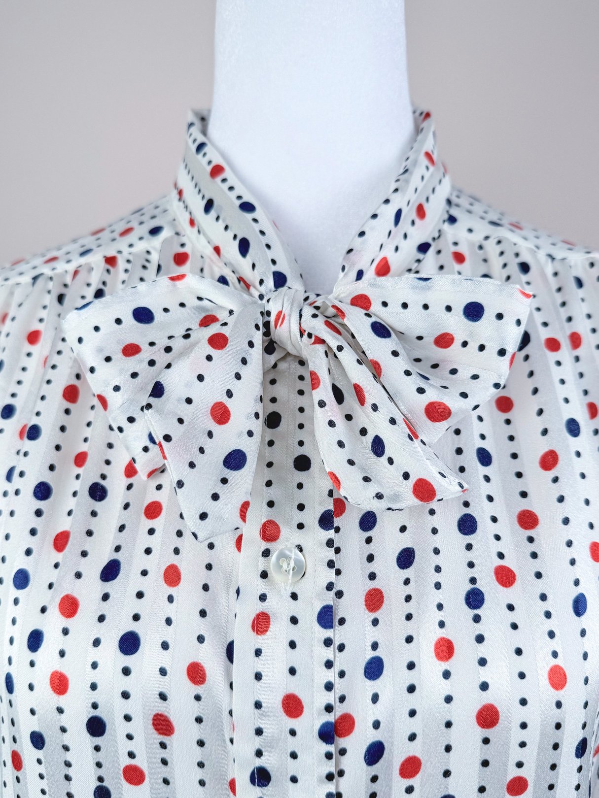 Red, white, and polka dot blouse with a bow tie collar, featuring vertical stripes of red, blue, and black dots.