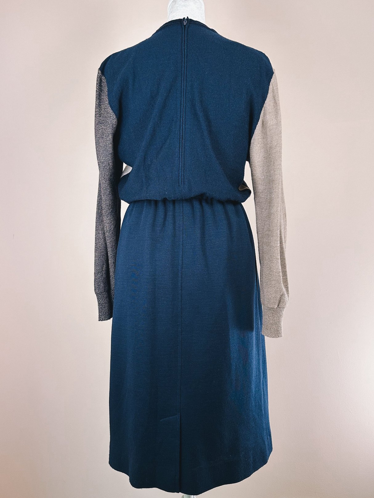 Navy blue 1980s women’s sweater dress with a fitted waist and contrasting gray sleeves.