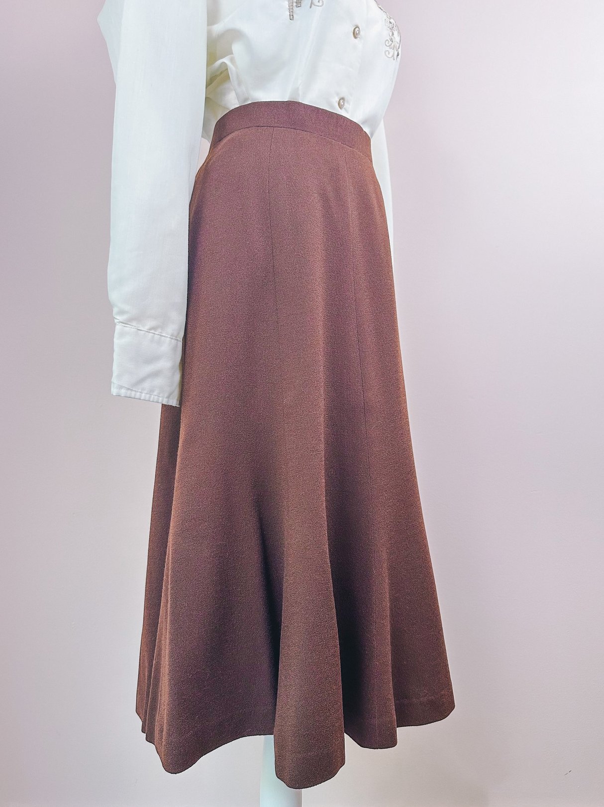 Brown 1970s women’s skirt with a flared silhouette, shown on a mannequin alongside a white blouse.