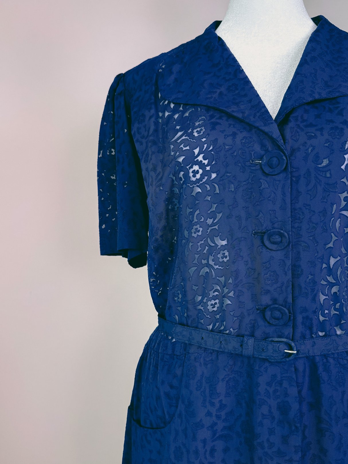 Navy blue women's dress from the 1940s featuring short sleeves, a button-up front, and a belted waist.