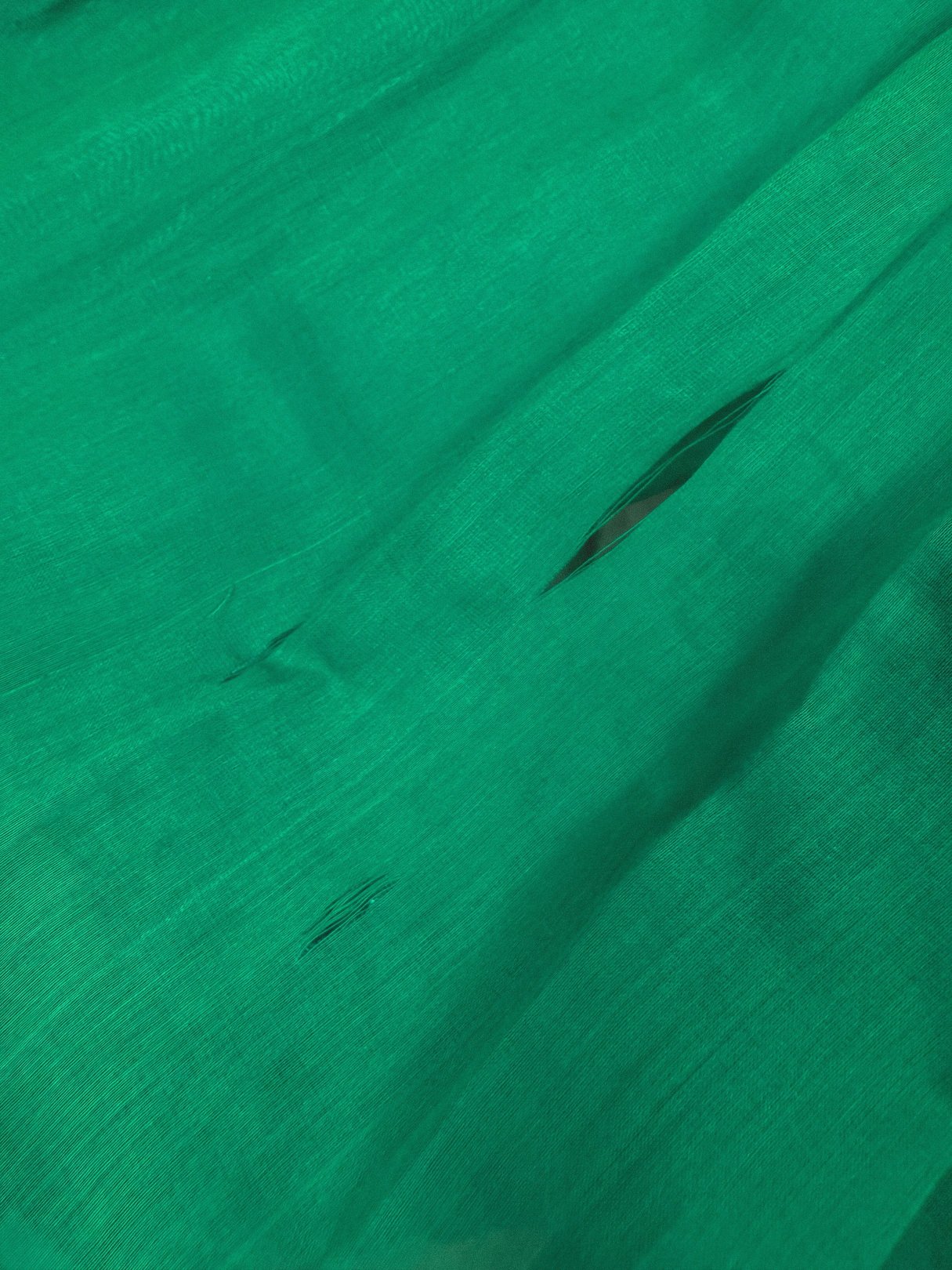 Emerald green fabric with a smooth texture featuring small, dark motifs.