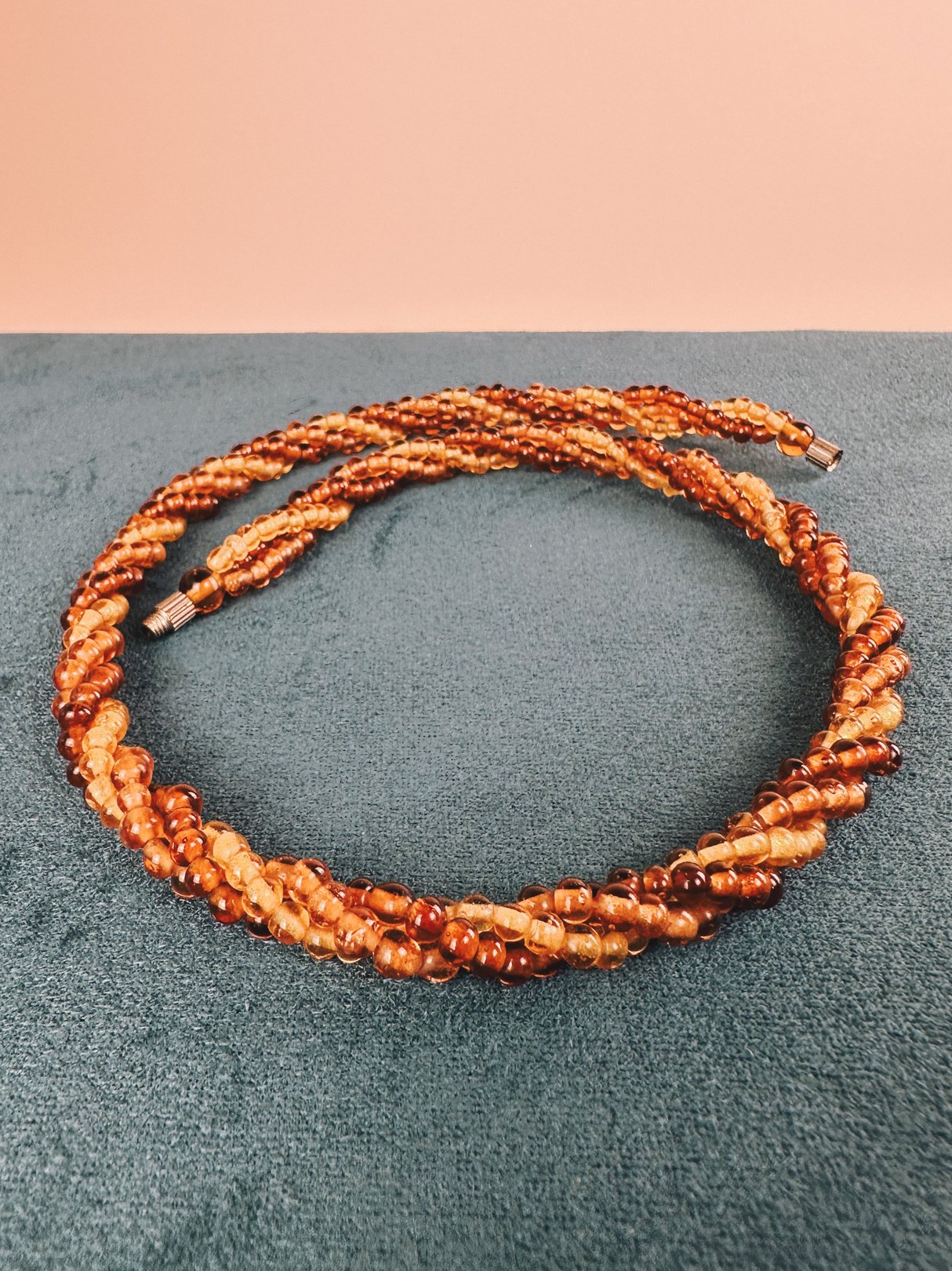 1970s women’s amber beaded necklace featuring twisted strands of varying shades of amber.
