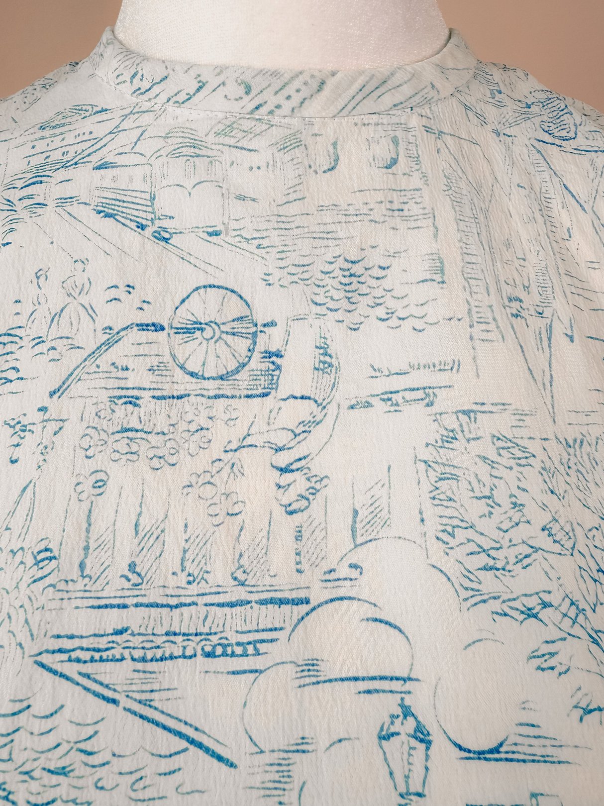 The Paris Montage Dress features a blue, 1960s-inspired design with a scenic print of landscapes and floral elements.