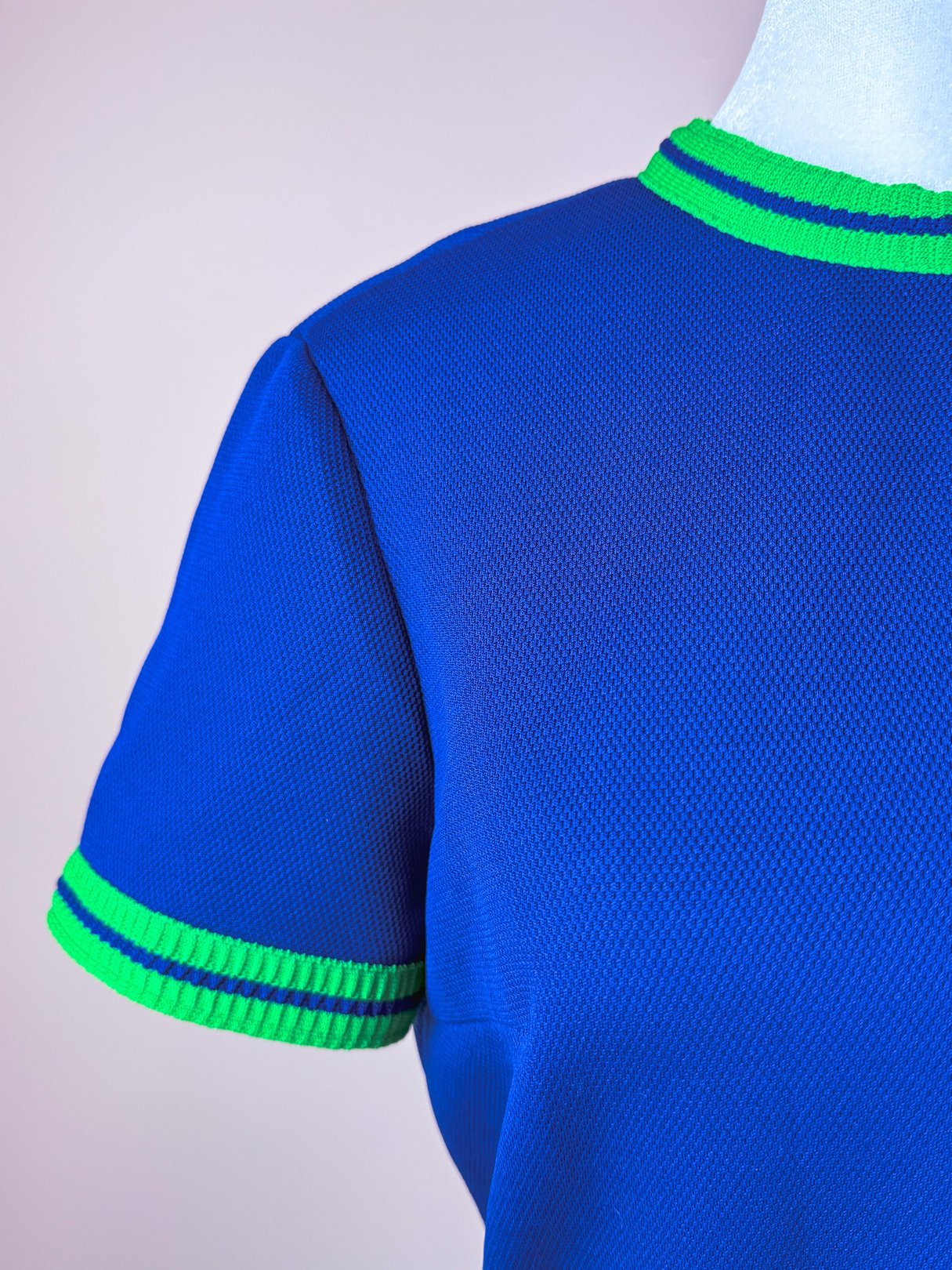 The Pacific Lines Dress features a blue fabric with green ribbed trim on the neckline and sleeves, embodying a 1970s style.